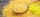 yellow mustard seeds spilling out of a large wooden spoon